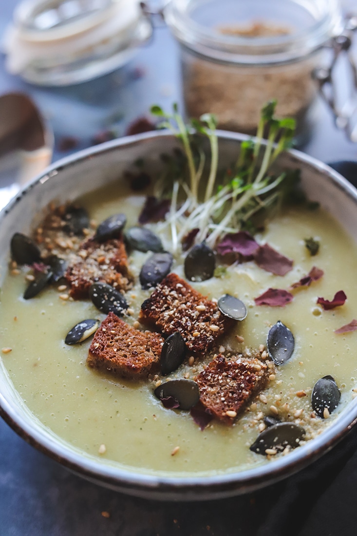 Soupe crémeuse microbiote friendly au bouillon d'os et de viande avec croûtons au levain, graines de courge et pousses fraîches, idéale pour la santé intestinale.