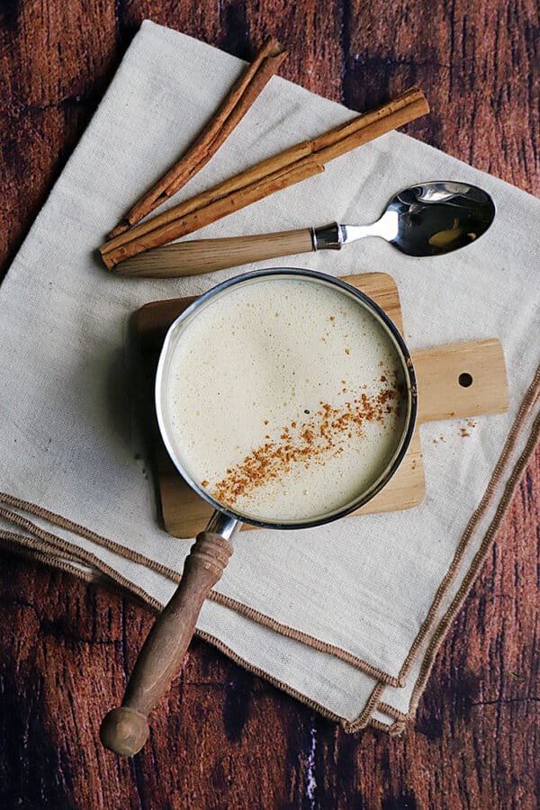 recette de Crème anglaise crémeuse avec une pincée de cannelle dans une casserole avec des bâtons de cannelle.