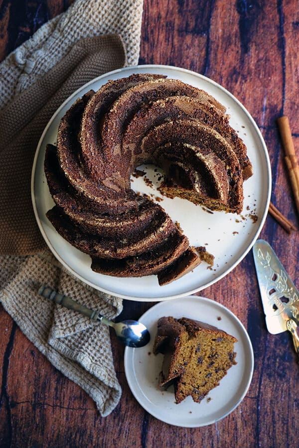 Gâteau marbré automnal sur un plat, avec une tranche servie sur une petite assiette, prêt à déguster.