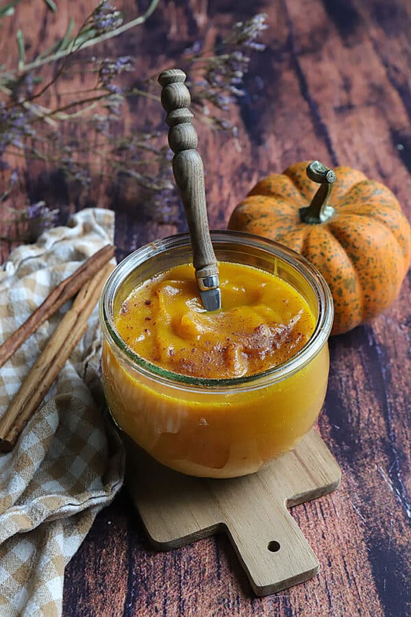 Purée de courge aux épices dans un pot en verre avec une cuillère en bois.